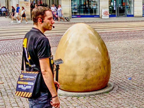 unser Stadtführer steht vor einem großen messingfarbenen Ei